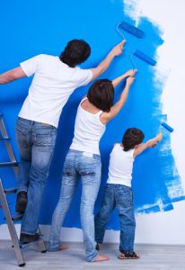 Man woman and boy painting a wall blue