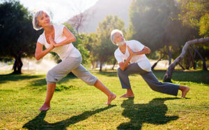 Yoga at park. Senior family couple exercising outdoors.